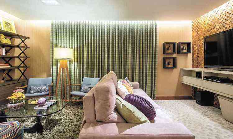 Projeto da designer de interiores Melina Mundim, a cortina em tom de verde na sala foi acompanhada por pontos de cor em detalhes, como nas almofadas e no abajur - 
